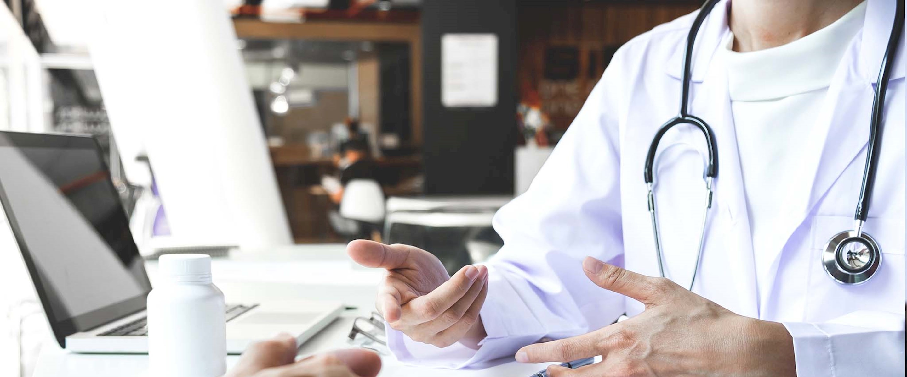 Closeup of a doctor sitting across the desk from a patient