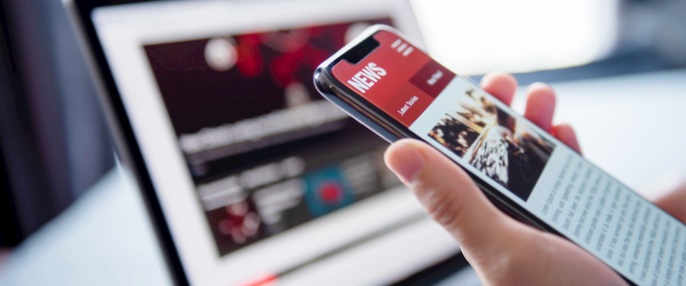 A hand holding a smartphone in front of a laptop